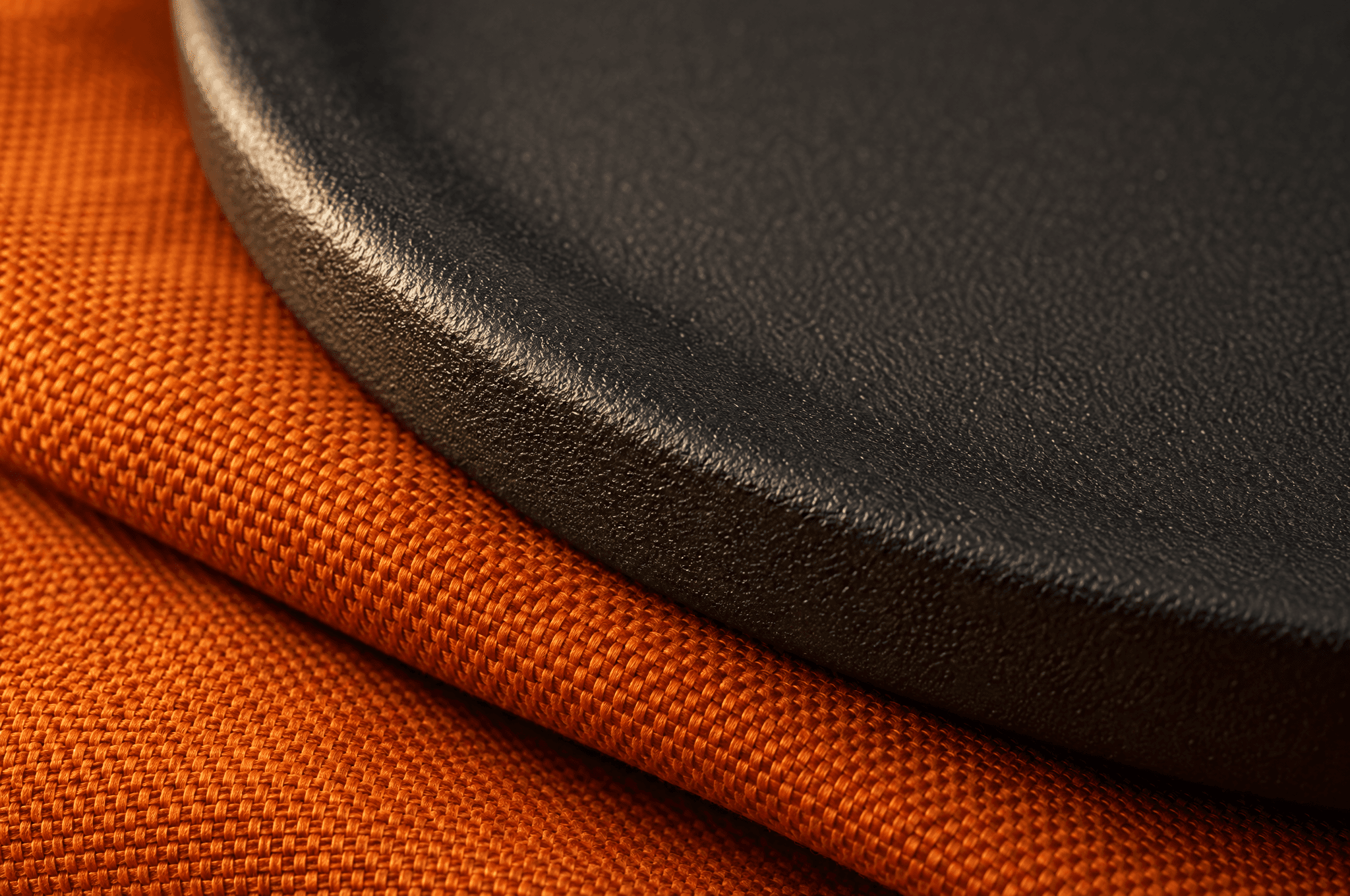 Close view of the matte charcoal surface of a curved iron plate resting on folded orange fabric.